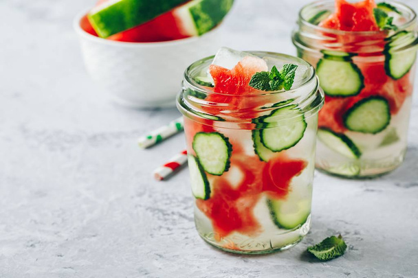 Geïnfundeerd detox water met watermeloen, plakjes komkommer en munt. Ice koude zomer cocktail of limonade in glazen mason jar - Foto, afbeelding