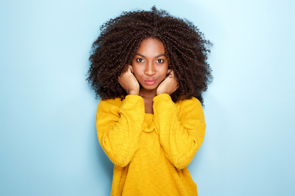 Portret van mooie jonge Afrikaanse vrouw houden oren op blauwe achtergrond - Foto, afbeelding