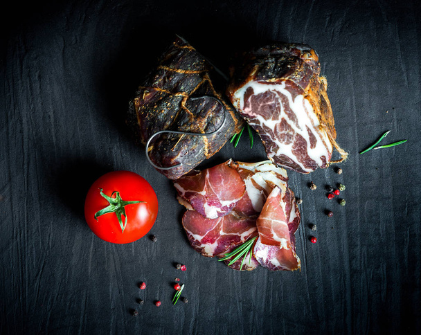 A set of different types of raw smoked meat. Jamon Lomo, oppa and fillet on a black background.  - Foto, Imagem
