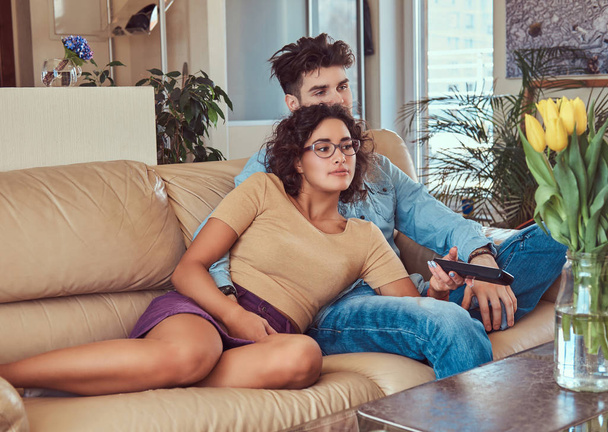 Young couple cuddling while watching TV at home. - Photo, Image