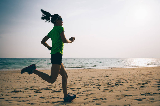 Young fitness woman running on sandy beach - Photo, image