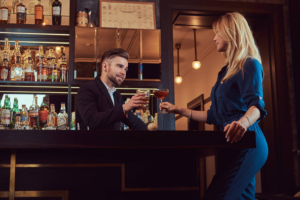 Κομψό ζευγάρι είναι οι δαπάνες το βράδυ σε ένα ρομαντικό περιβάλλον, πίνοντας κρασί στο μπαρ του μετρητή. - Φωτογραφία, εικόνα
