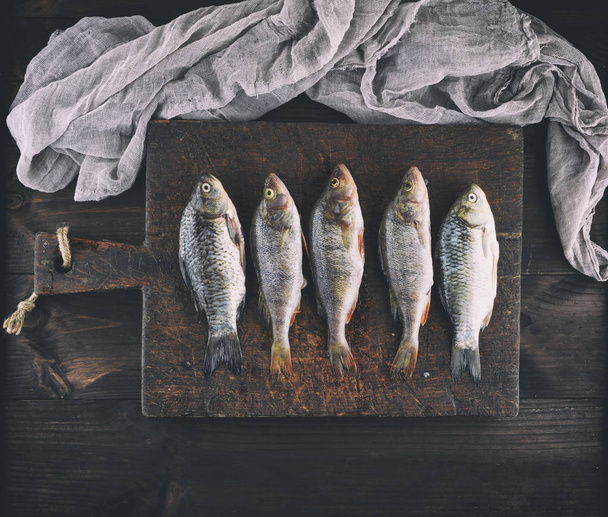 fresh fish perch and carp cleaned from scales lie on a brown wooden board, top view, vintage toning - Foto, immagini