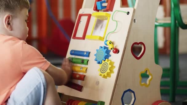 Ein kleiner Junge im Kindergarten spielt ein sich entwickelndes Spielzeug - Filmmaterial, Video