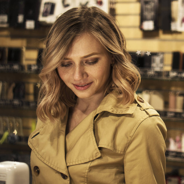 Portrait of Attractive Young Blonde Woman in Trench visiting Shop - Фото, зображення