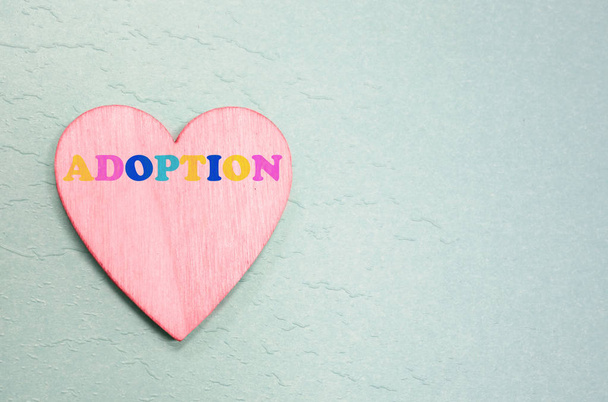 Pink heart with colorful adoption text on blue                                - Photo, image