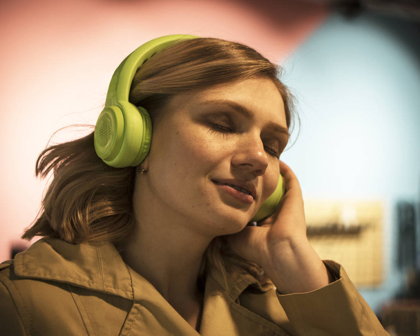 Πορτρέτο του ελκυστική νεαρή ξανθιά γυναίκα στο χαράκωμα προσπαθεί ακουστικά - Φωτογραφία, εικόνα