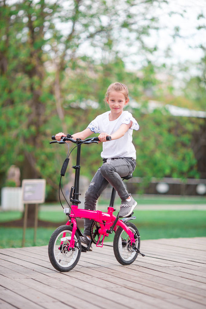 Adorable girl riding a bike at beautiful summer day outdoors - Photo, Image