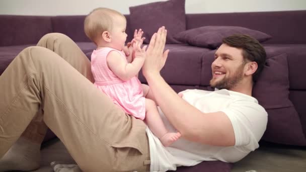 Papa mit Baby beim Händespielen. Lächelnder Vater und Kleinkind spielen mit den Händen - Filmmaterial, Video