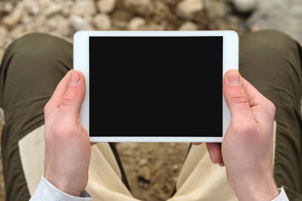Tableta digital con pantalla aislada en manos masculinas sobre el fondo de la cafetería - mesa, taza de café
. - Foto, imagen