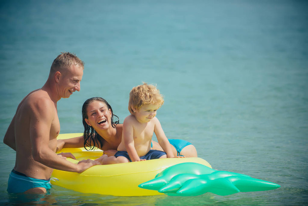 カリブの海に幸せな家族カップル。パイナップル インフレータブルまたはエアコンのマットレス。モルディブまたはマイアミ ビーチ活動の喜び。父と息子と母は、水で遊ぶ。夏休み、海への旅行. - 写真・画像