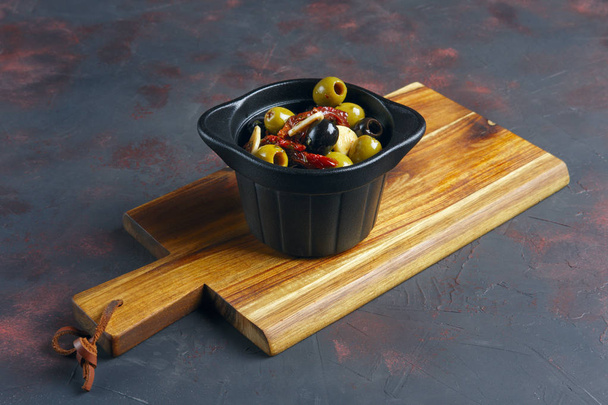 Black and green olives in Spanish on wooden plate - Zdjęcie, obraz