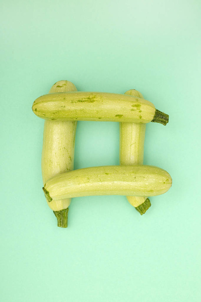 vier reife Zucchini gestapelt auf grünem Hintergrund - Foto, Bild