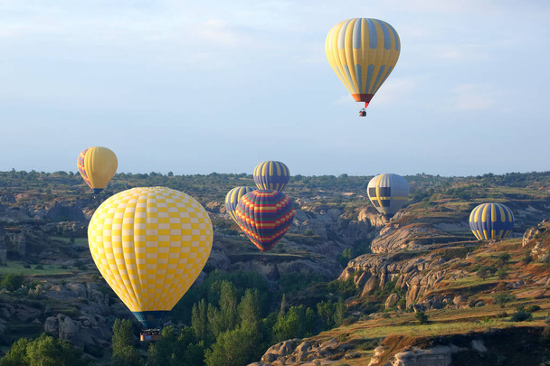 Kleurrijke ballons met mensen vliegen in de vallei in Cappadocië - Foto, afbeelding