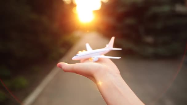 Toy airplane in the palm of a girl on a sunset background. - Footage, Video