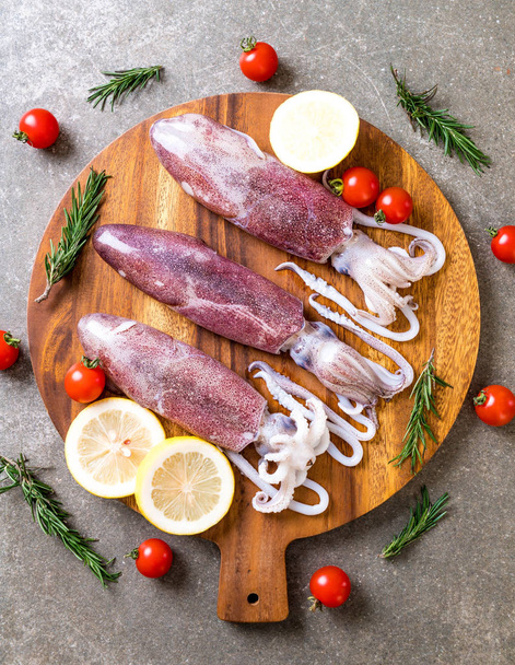 fresh octopus or squids raw on wooden board with ingredients - Zdjęcie, obraz