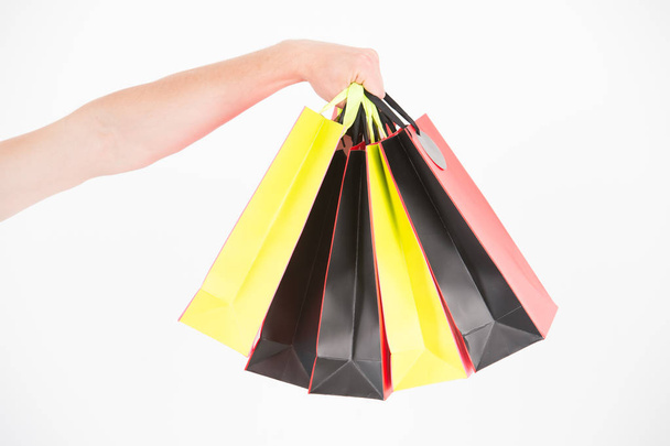 Male hand holds five shopping bags. Shopping concept. Hand holds bunch of colorful shopping bags. Shopping on black friday. Client bought lot items with discount - Foto, Imagem