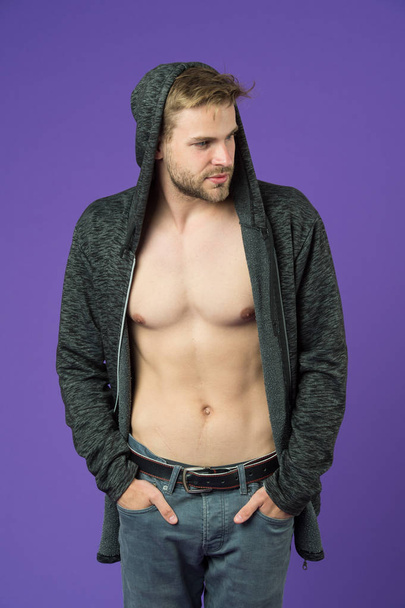 Macho with sexy torso in casual sweatshirt. Man with beard wear hood on violet background. Fashion model in hoodie. Active lifestyle and health activity. Fashion style and trend concept - Foto, immagini