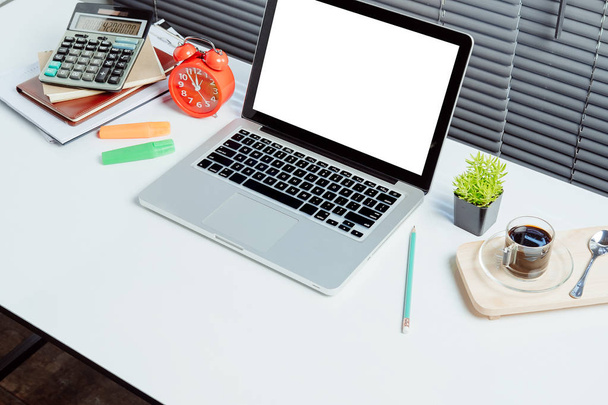 空白の画面のラップトップコンピュータ、コーヒーとオフィス用品とモダンな白い木製のテーブル。製品表示用デスクワークスペースモックアップ. - 写真・画像