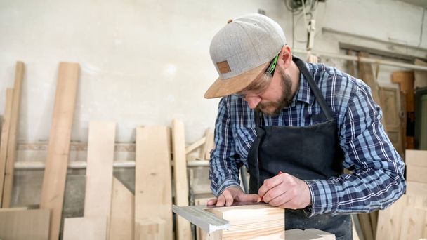 Close-up van werkman handen in handschoenen houten plank meten met de liniaal en potlood op de werkbank. Concept van houtbewerking en handwerk. - Foto, afbeelding