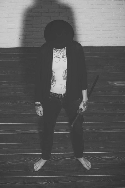 Serious man. Man with sword standing on wooden floor barefoot, top view - Valokuva, kuva