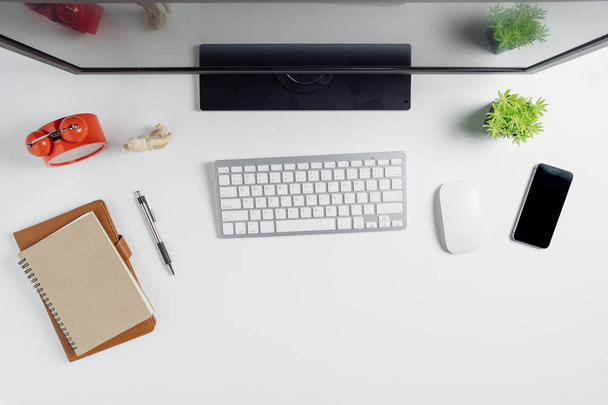 Современный белый офисный стол с компьютером, смартфоном, ноутбуком и чашкой кофе.. - Фото, изображение