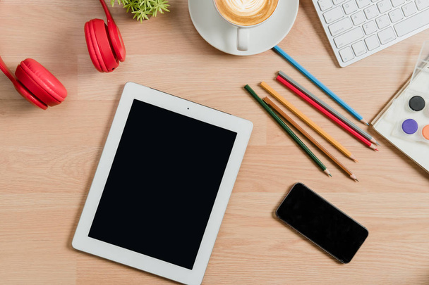 Γραφείο με χρωματιστά μολύβια, έγχρωμο νερό, σημειωματάριο, μολύβι, tablet, smartphone και φλιτζάνι καφέ.. - Φωτογραφία, εικόνα