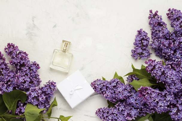 Perfume bottle and white gift box, lilacs on a light stone background. - Photo, Image