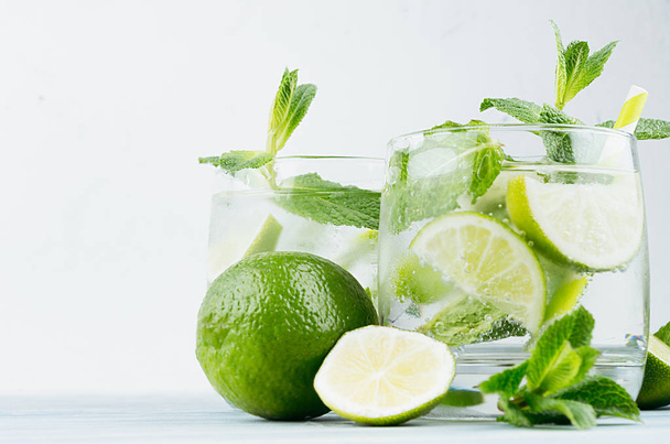 Tropical fresh cold cocktail with mint, lime, ice, straw on light white plaster background, copy space, closeup. - Φωτογραφία, εικόνα