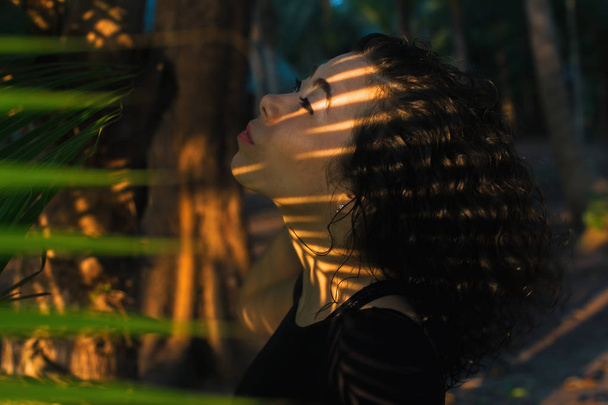 Молодая женщина смешанной расы среди листьев пальм
. - Фото, изображение