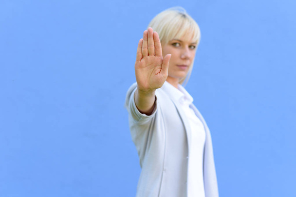 Donna bionda che dà un segno di stop o un gesto estendendo il palmo della mano si concentrano a mano
 - Foto, immagini