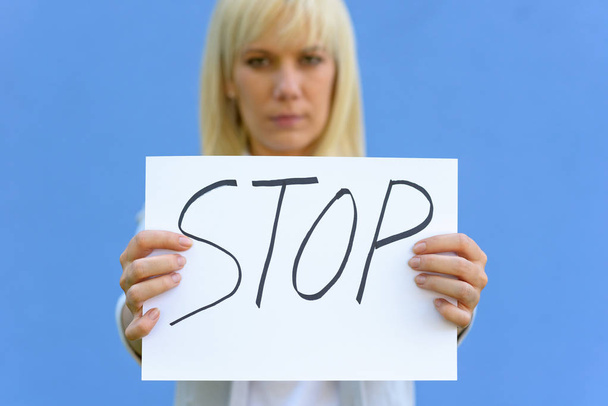 Giovane donna severa che regge un segnale di stop scritto a mano su carta con focus per firmare
 - Foto, immagini