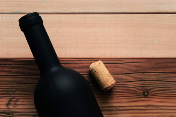 Black bottle of red wine on a new and red wooden table. Beautiful  background - Φωτογραφία, εικόνα