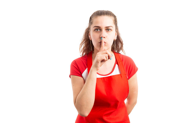 Young female supermarket or hypermarket employee making shush gesture as silence shut up concept isolated on white background - Photo, Image