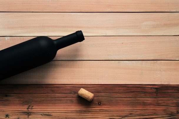 Black bottle of red wine on a new and red wooden table. Beautiful  background - 写真・画像
