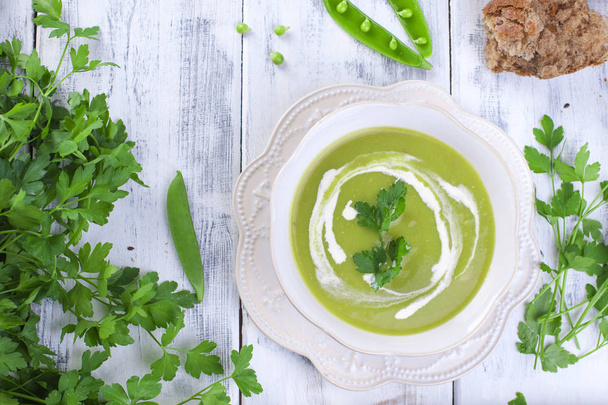 Cream soup of green peas and Parsley. Healthy lunch in a white plate on a white wooden background, Copy space - Foto, Imagem