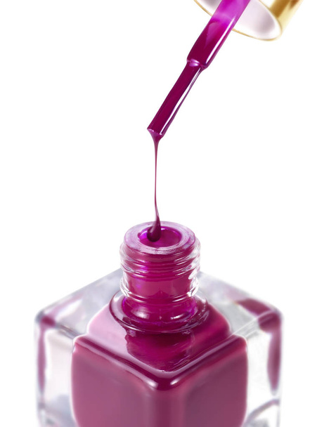 Rode nagellak druipend tegen fles - Foto, afbeelding