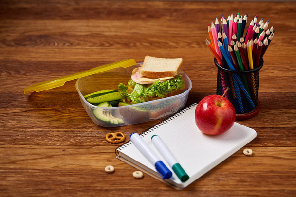 Back to School concept, school supplies, biscuits, packed lunch and lunchbox on white desk, selective focus, close-up. - Fotó, kép