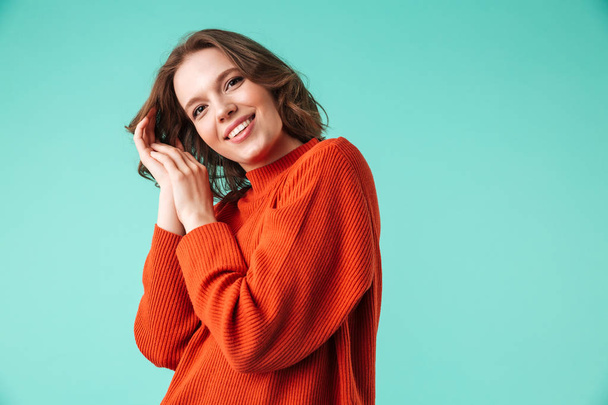 Portrait of a cheerful young woman dressed in sweater looking at camera isolated over blue background - Foto, Imagem