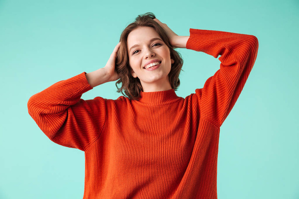 Portrait of a happy young woman dressed in sweater looking at camera isolated over blue background - Фото, изображение