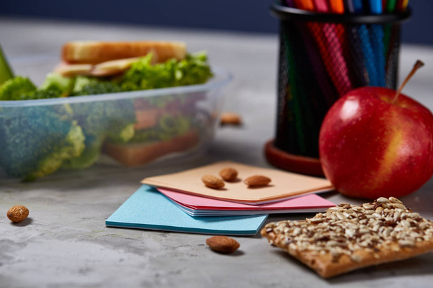 Back to School concept, school supplies, biscuits, packed lunch and lunchbox over white chalkboard, selective focus. - Foto, Bild