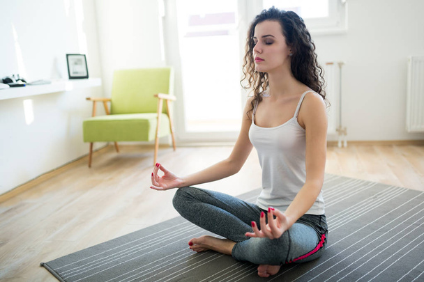 Young attractive woman relaxing and practicing yoga at home - Foto, afbeelding