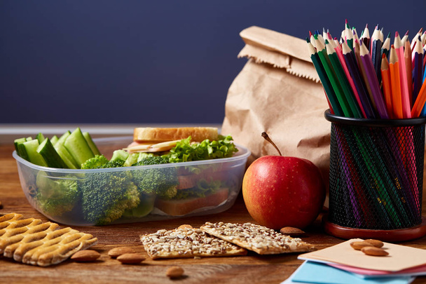 Back to School concept, school supplies, biscuits and lunchbox on wooden desk, selective focus, close-up. - Foto, Bild