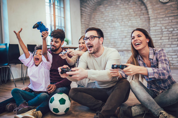 Two mixed race couple play video games with their children, having fun. - Photo, Image