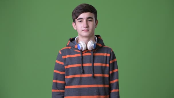 Νεαρό όμορφος ιρανική εφηβικό αγόρι ενάντια σε πράσινο φόντο - Πλάνα, βίντεο