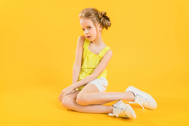 Uma adolescente está sentada em um fundo amarelo
. - Foto, Imagem