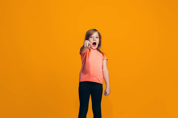The happy teen girl pointing to you, half length closeup portrait on orange background. - Фото, изображение