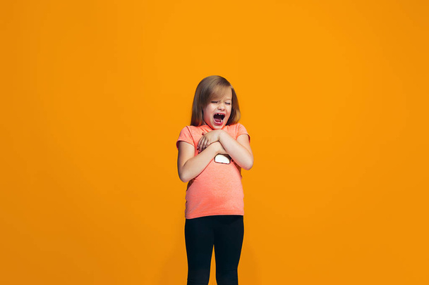 The happy teen girl standing and smiling against orange background. - 写真・画像
