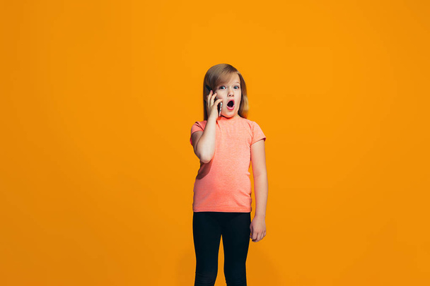 The happy teen girl standing and smiling against orange background. - Φωτογραφία, εικόνα