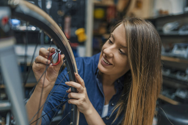 Making some adjustments to her bike. Girls can fix things too. Female Bicycle Mechanic. Young woman repairing bicycle. Repairing bicycle - Fotoğraf, Görsel